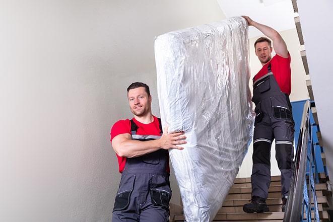 two workers hauling a box spring out of a building in Carmichael